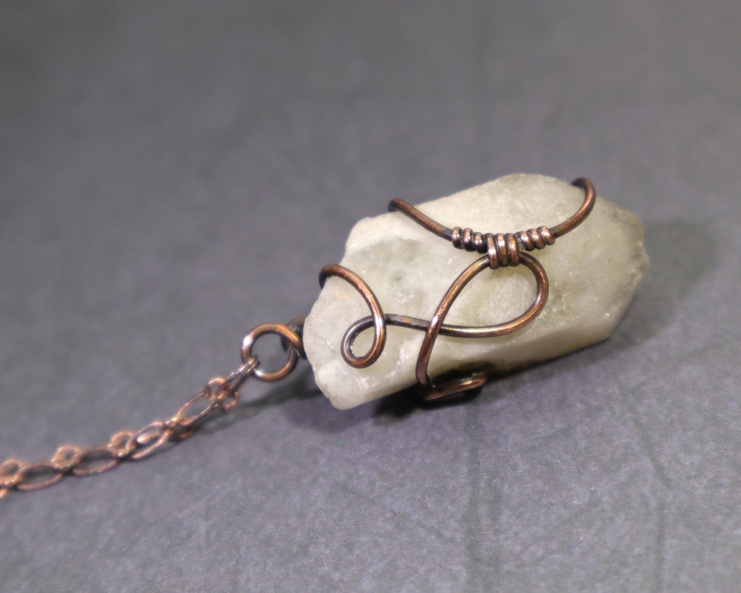 Copper-wrapped natural citrine stone pendant on a gray background