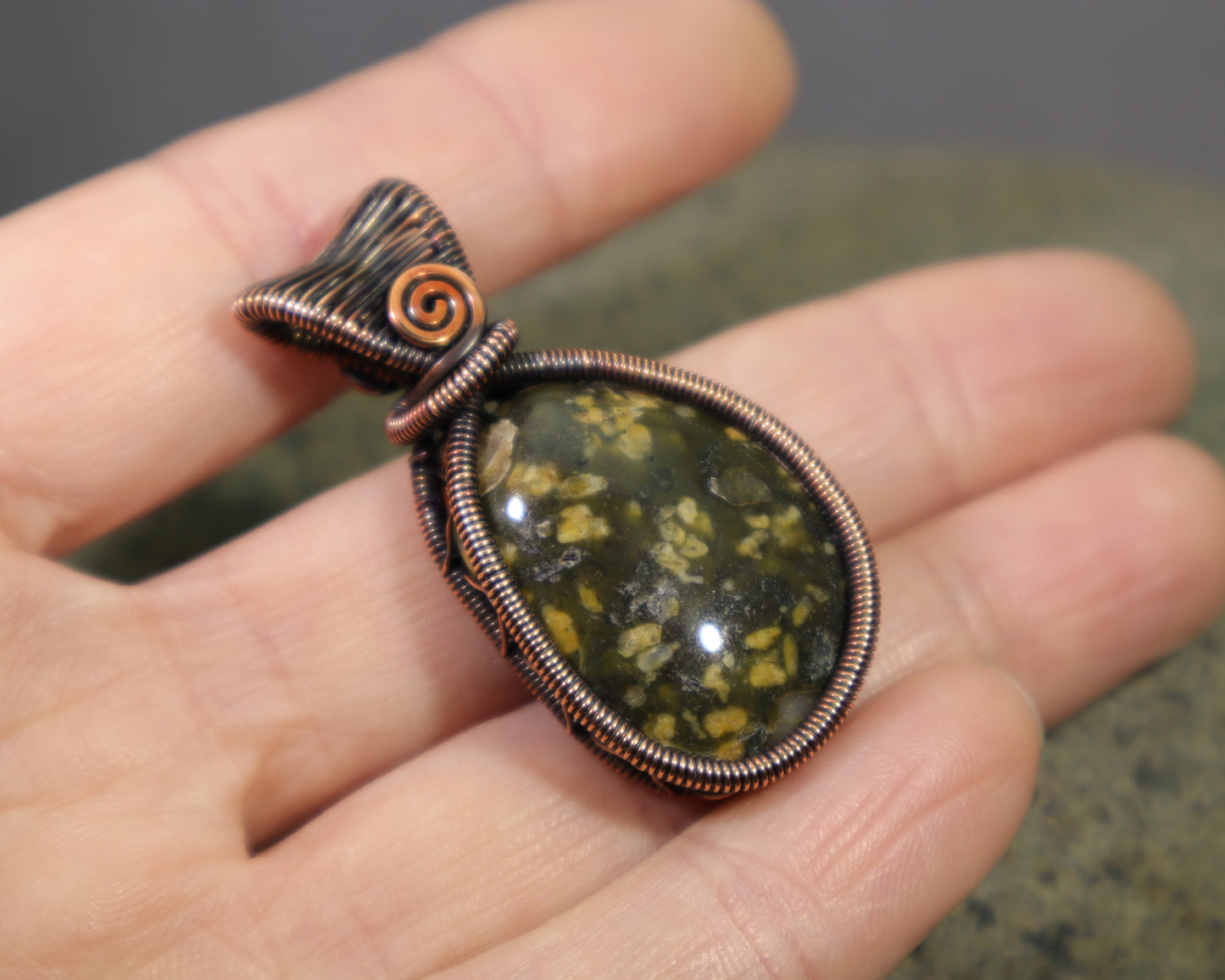 Green jasper pendant wire wrapped in copper from Washington State held in hand