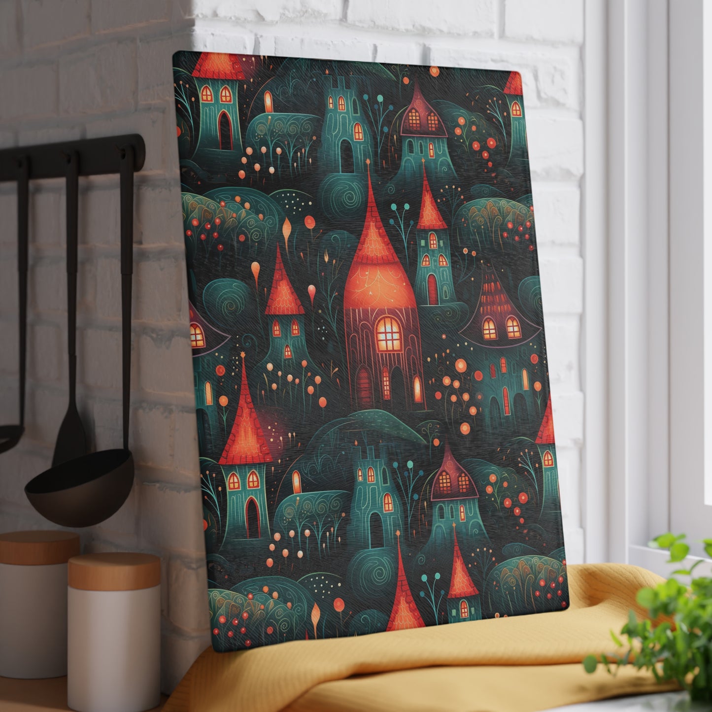 Rustic village-inspired glass cutting board propped against a white brick wall for a decorative look. Large size is 11 x 15 inches.