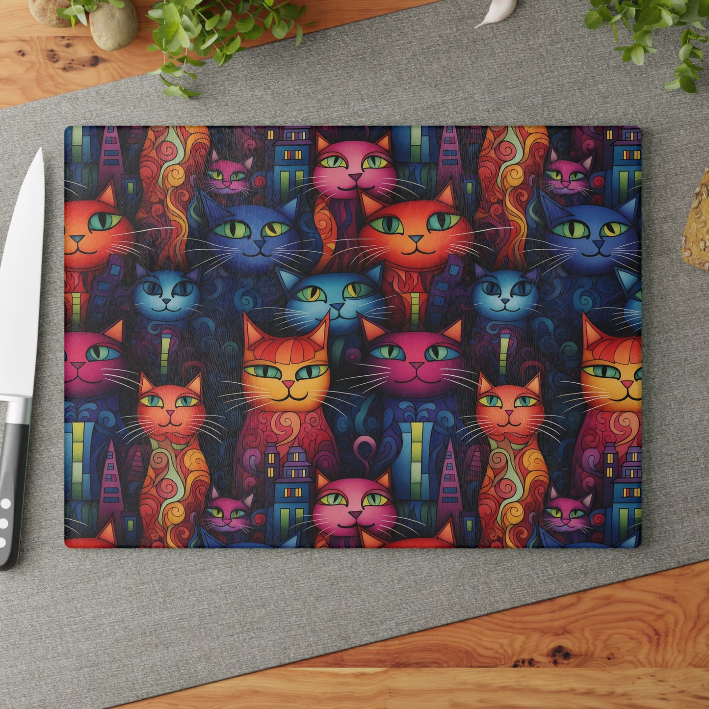 Cat glass cutting board styled on a countertop with a knife and fresh herbs. Large size is 11 x 15 inches.