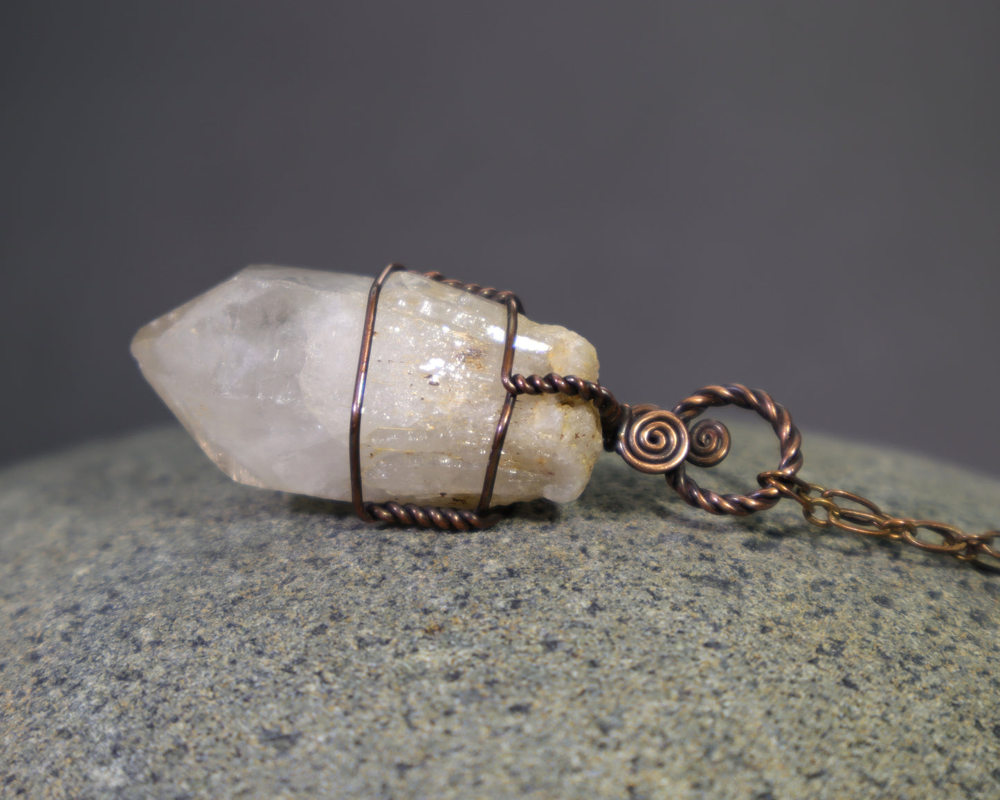 Raw natural citrine crystal pendant featuring unheated phantom candle quartz wire wrapped in oxidized copper.  The pendant sits on a stone surface.