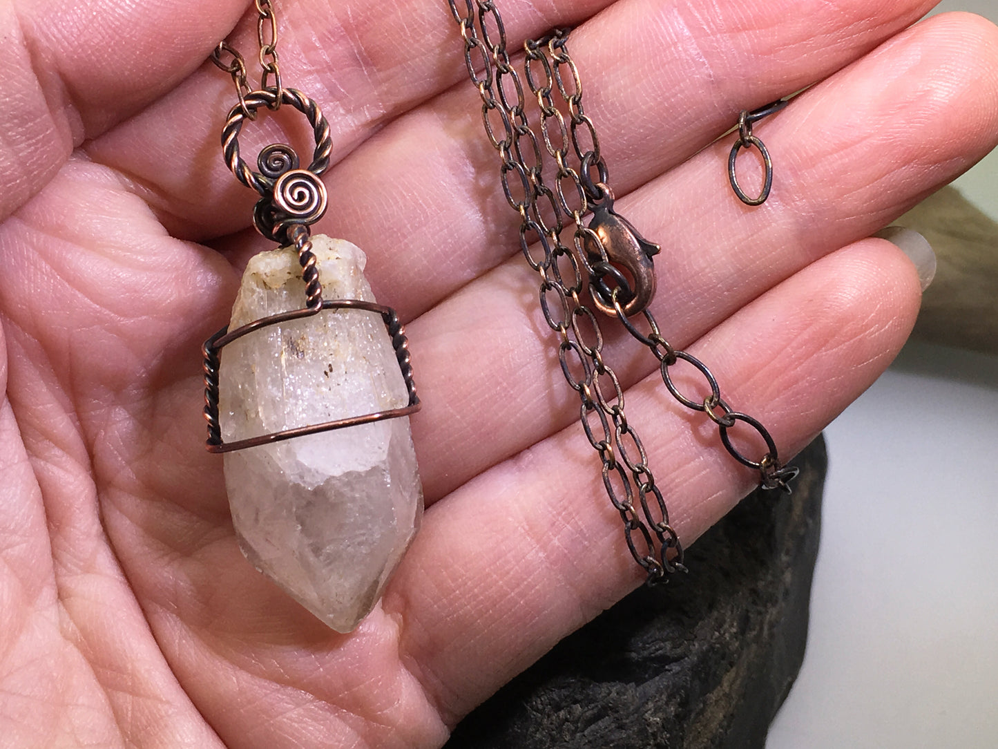 Necklace with a pale citrine crystal pendant and adjustable chain held in a hand