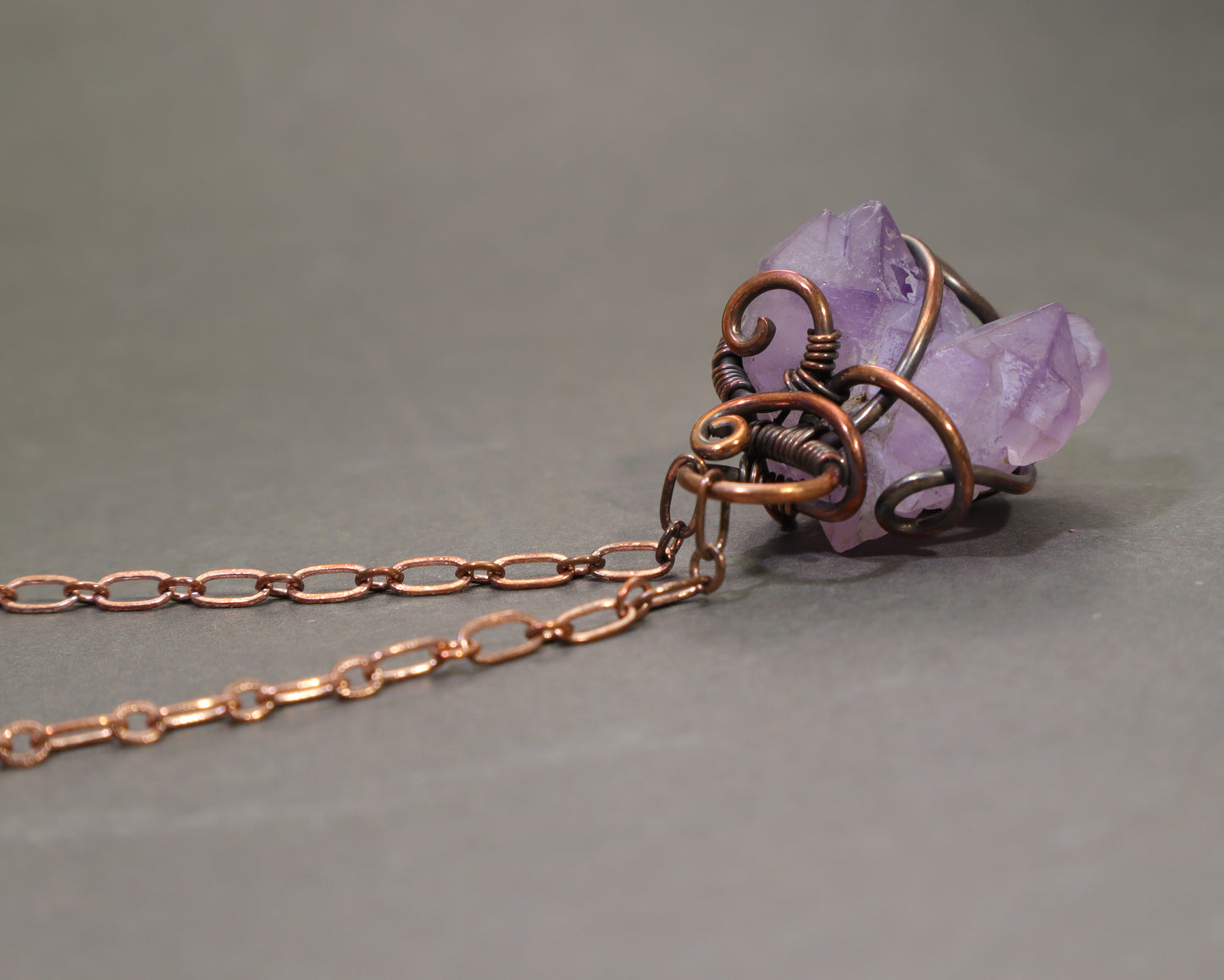 Wire Wrapped Raw Amethyst necklace on a gray background.