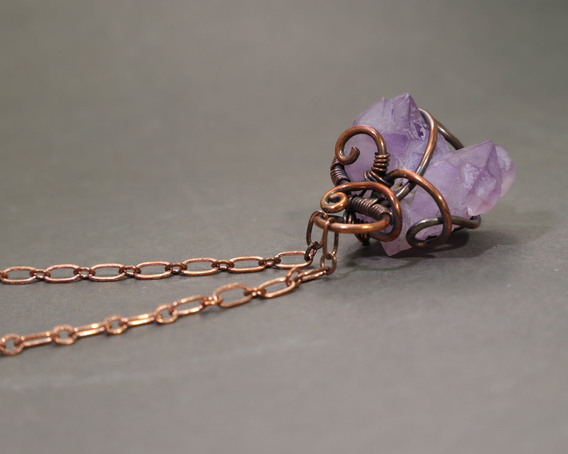 Wire Wrapped Raw Amethyst necklace on a gray background.