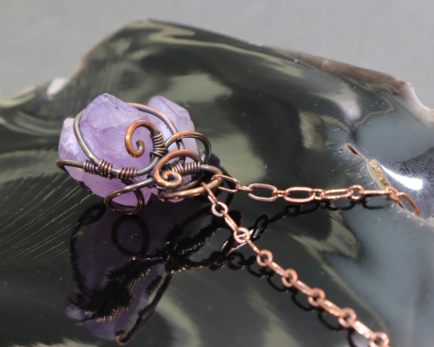 Raw amethyst wire-wrapped pendant with adjustable copper chain on black obsidian