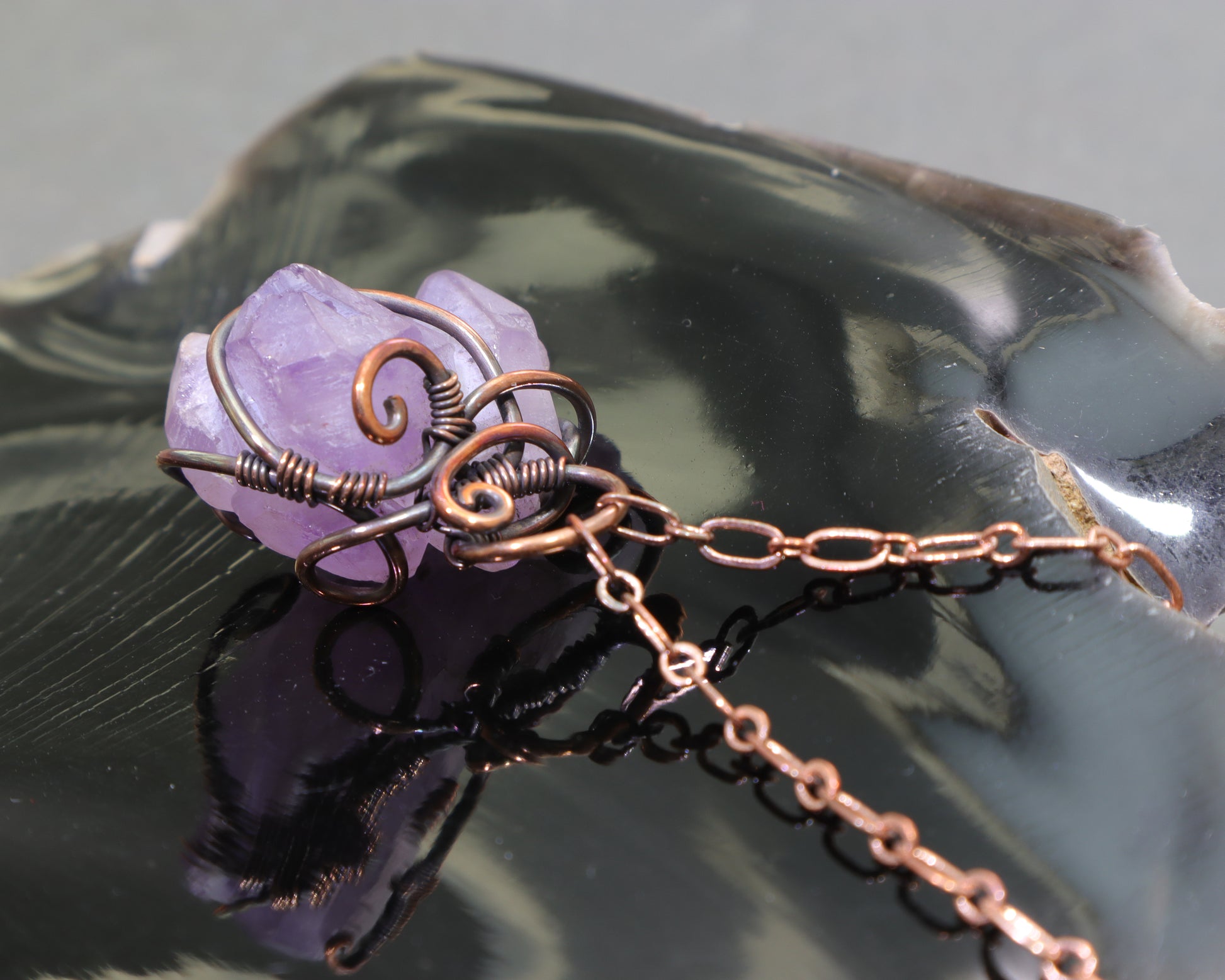 Raw amethyst wire-wrapped pendant with adjustable copper chain on black obsidian