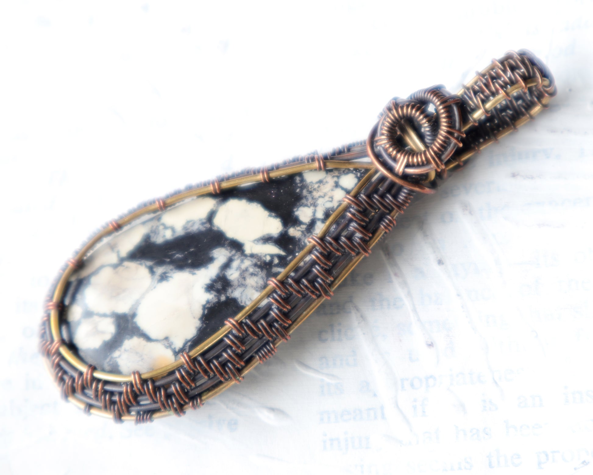 Magnesite map pendant wire wrapped in copper and brass on a white background