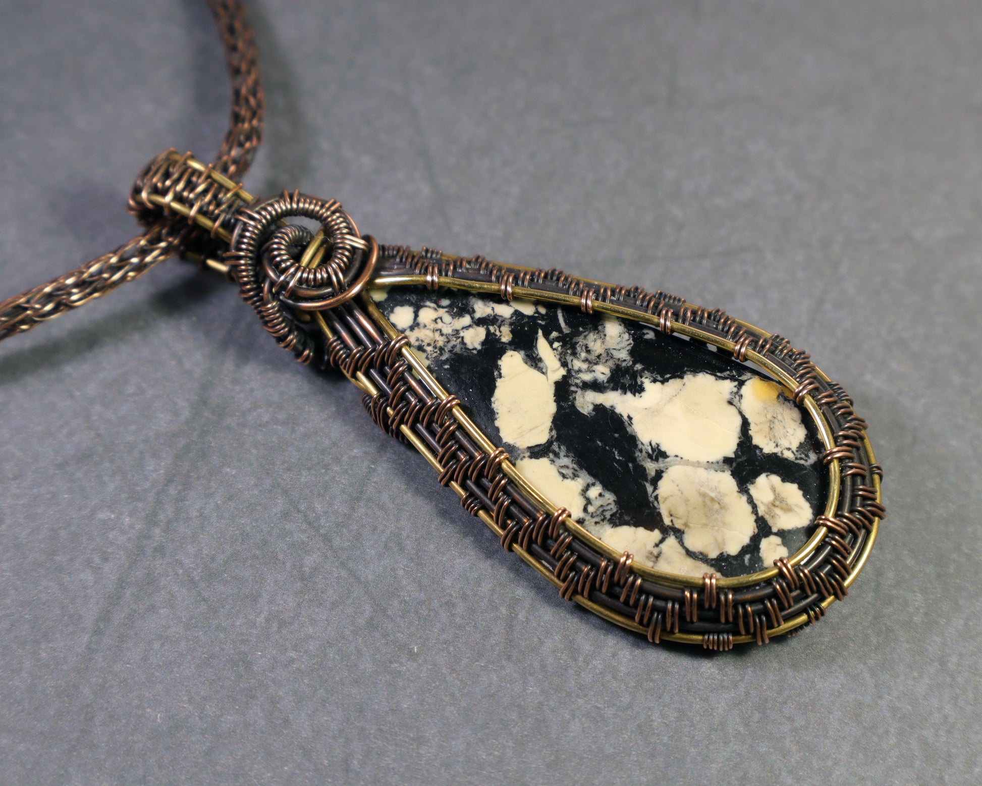 Front view of magnesite cabochon wire wrapped pendant on a dark gray background