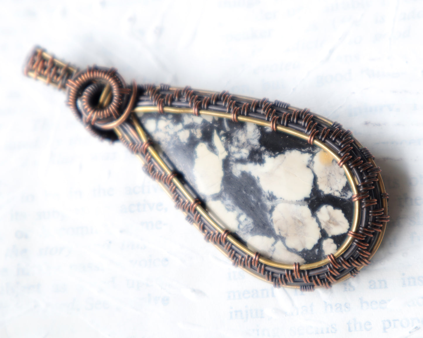 Handmade magnesite gemstone pendant with black and cream patterns on white background