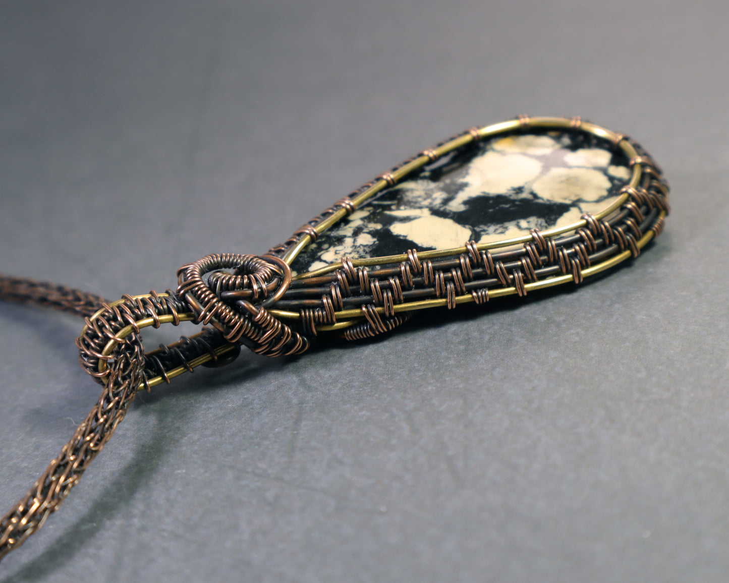 Top view of one of a kind magnesite pendant inspired by maps and landscapes on a gray background.