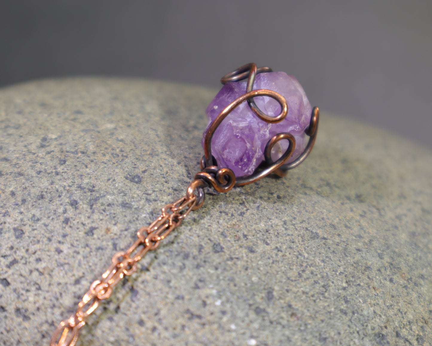 Top view of raw purple amethyst crystal necklace with antiqued copper wire wrapping