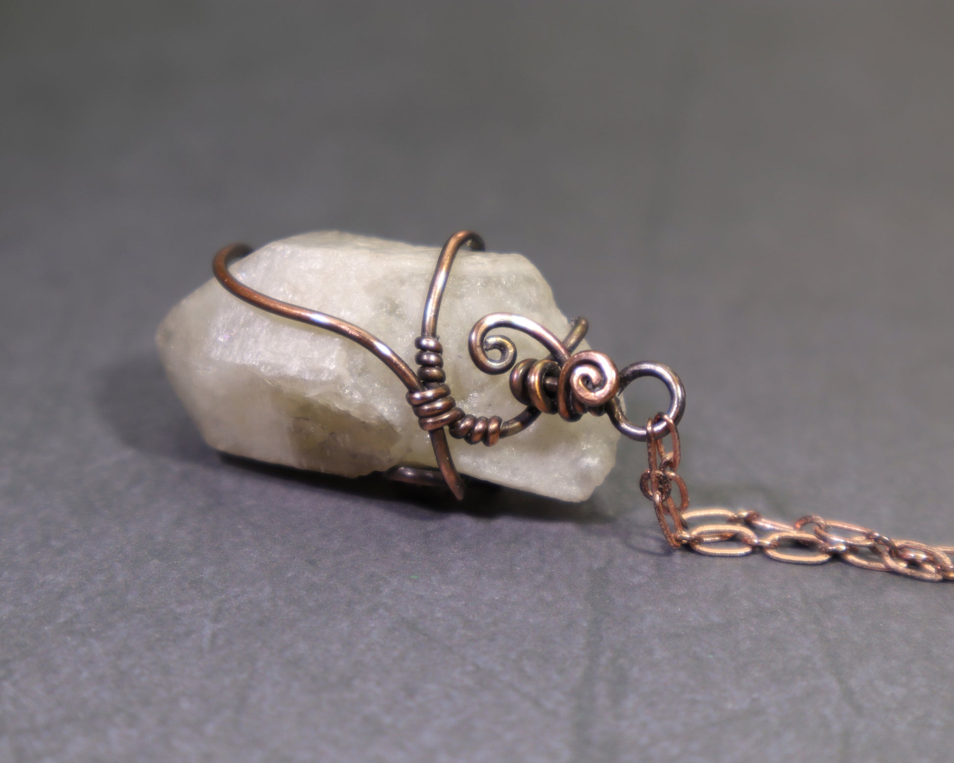 Back side view of natural rough citrine point pendant showing pale olive green crystal and copper wire wrap