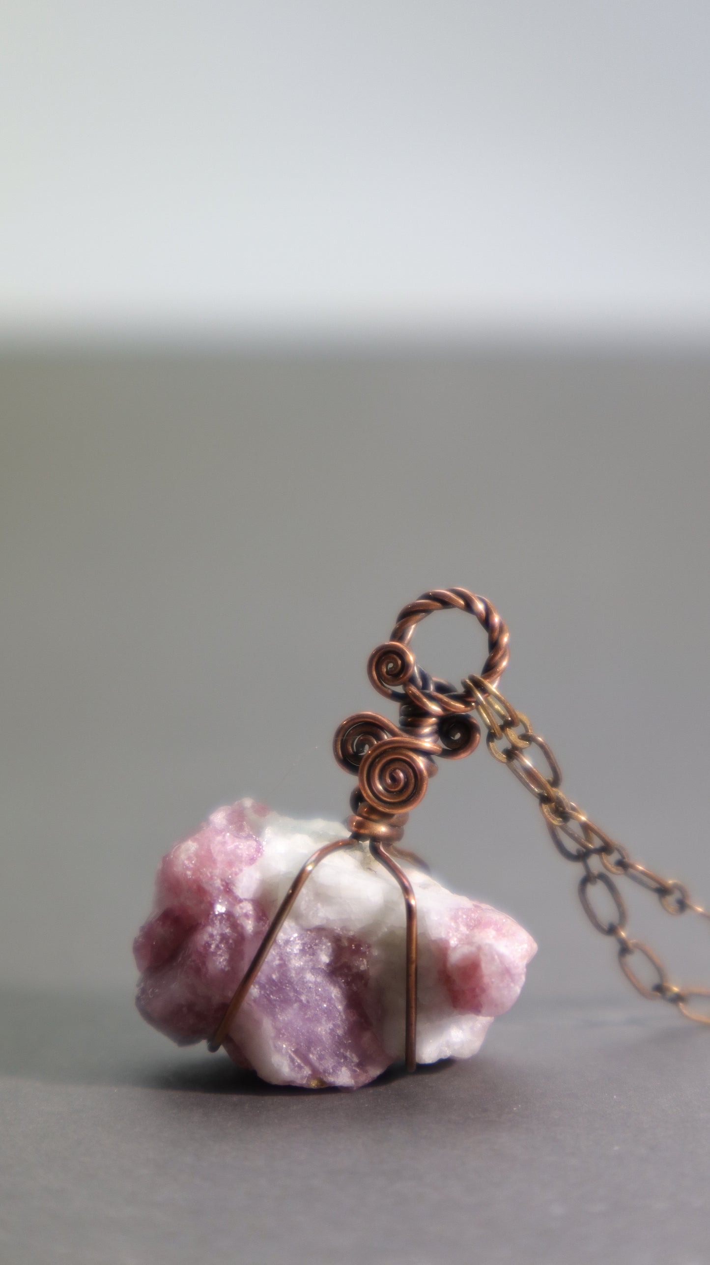 Raw pink tourmaline pendant necklace showcasing natural rubellite crystals in white albite matrix wire wrapped in oxidized copper wire.