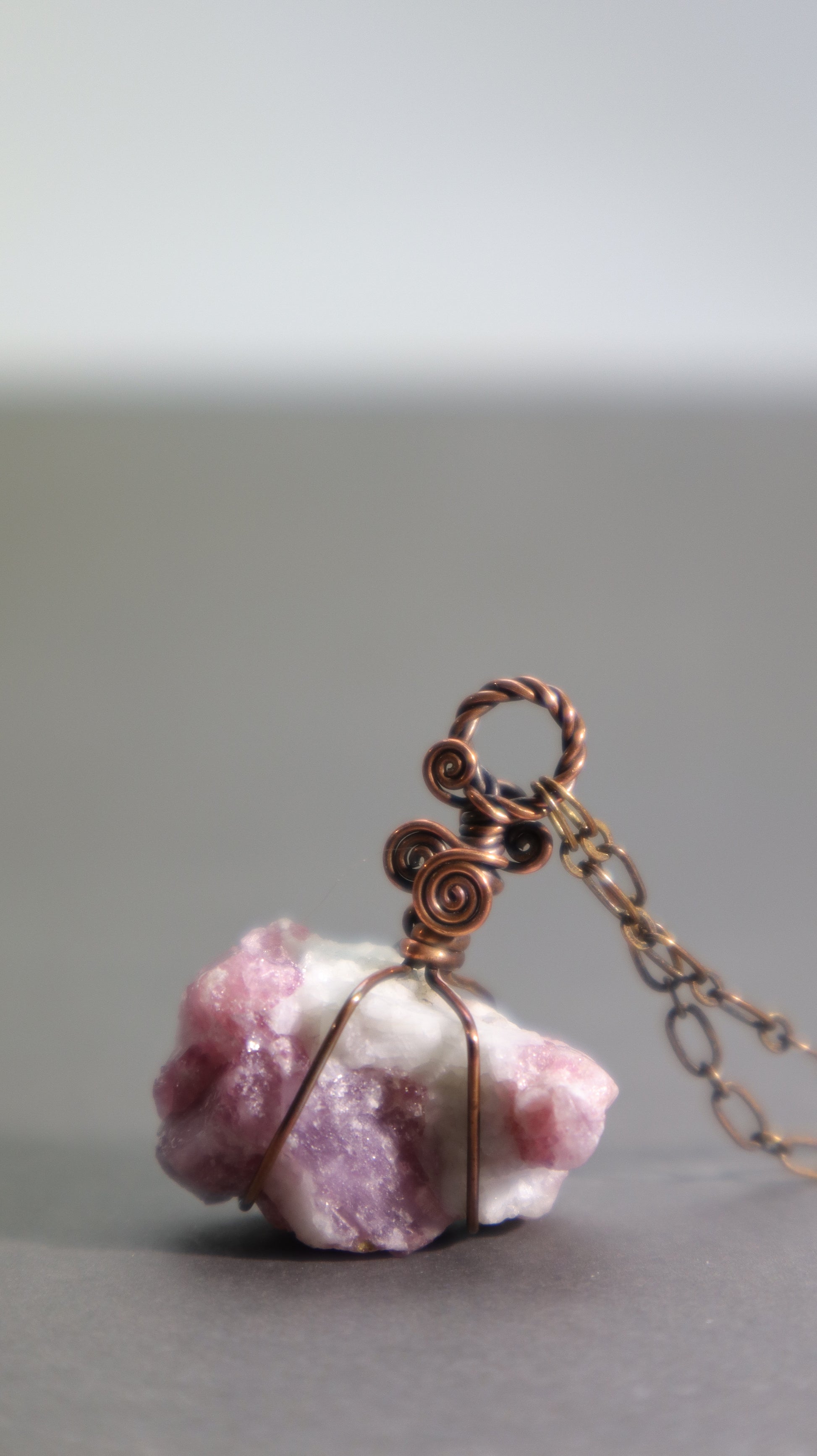 Raw pink tourmaline pendant necklace showcasing natural rubellite crystals in white albite matrix wire wrapped in oxidized copper wire.