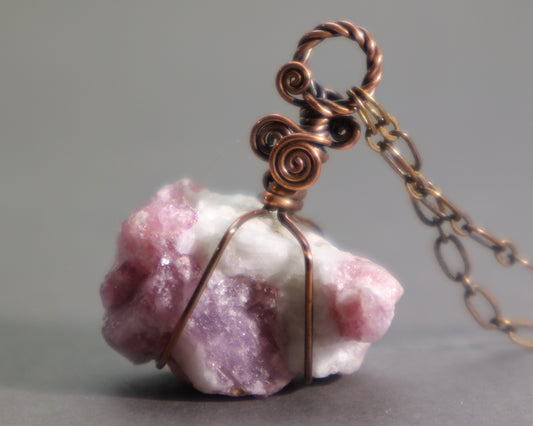 Raw pink tourmaline pendant necklace showcasing natural rubellite crystals in white albite matrix wire wrapped in oxidized copper wire.
