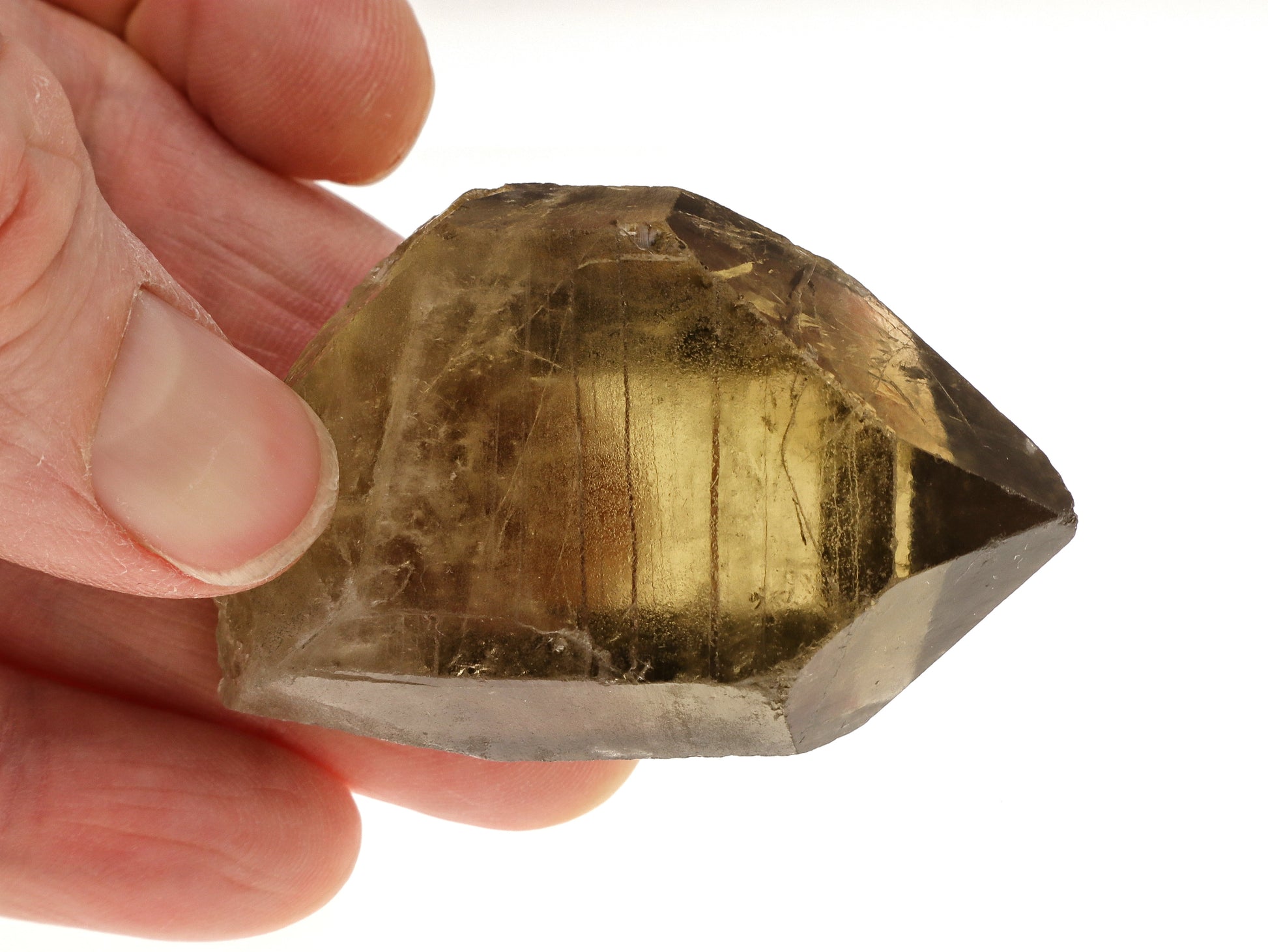 Hand holding a large, rough-cut citrine crystal against a white background