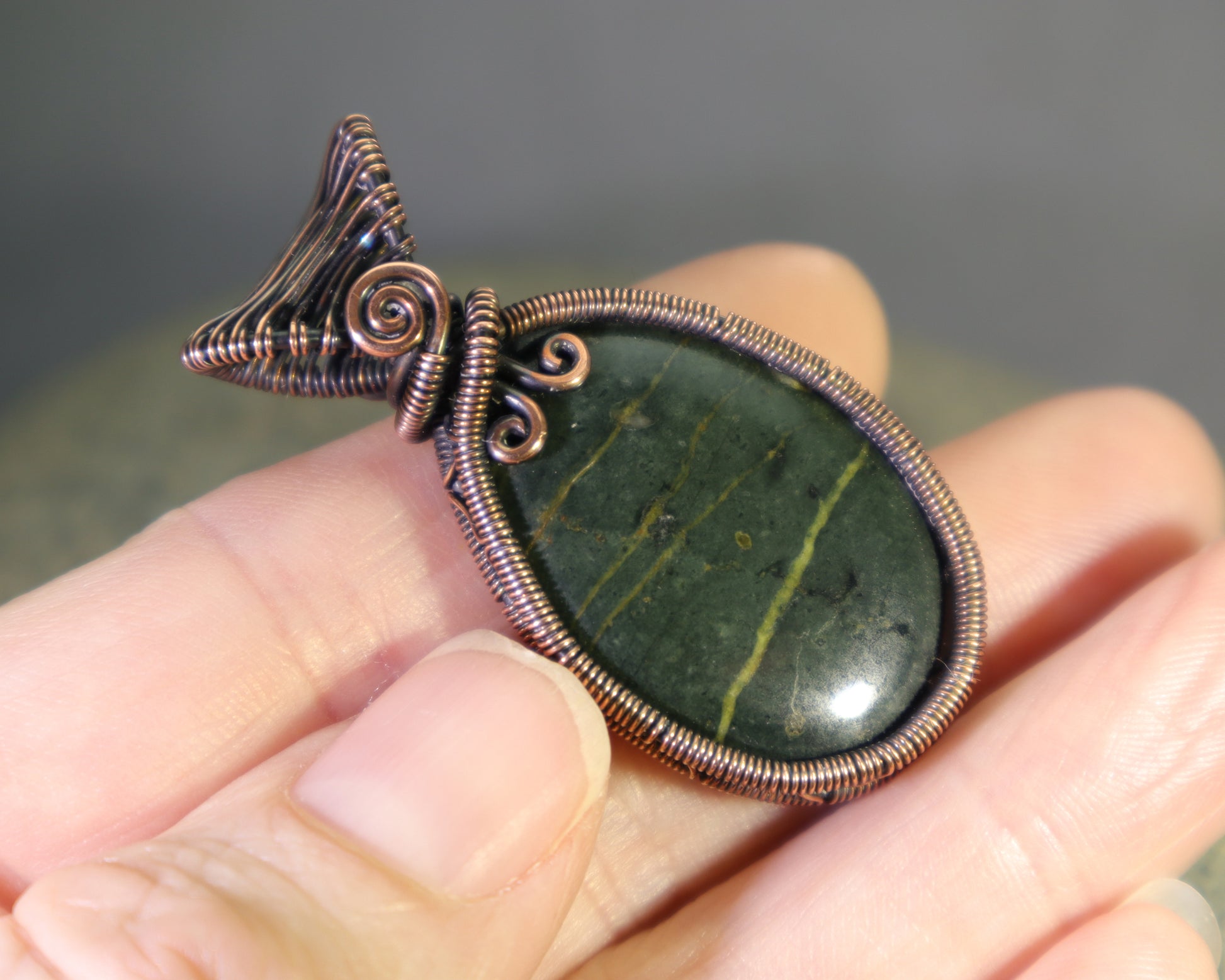 green heliotrope gemstone pendant with serpentine veining held in hand
