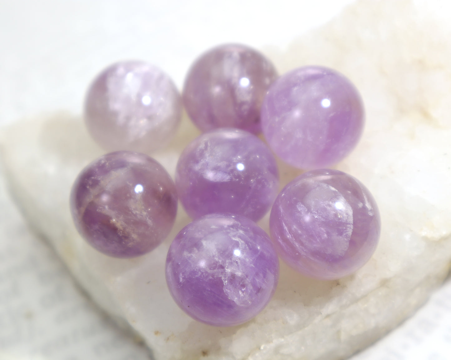 Purple amethyst gemstone spheres on a white stone surface