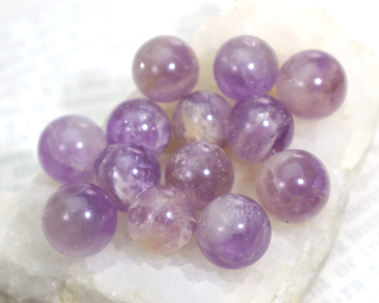 Purple quartz meditation spheres with white veining on a white crystal cluster and white background