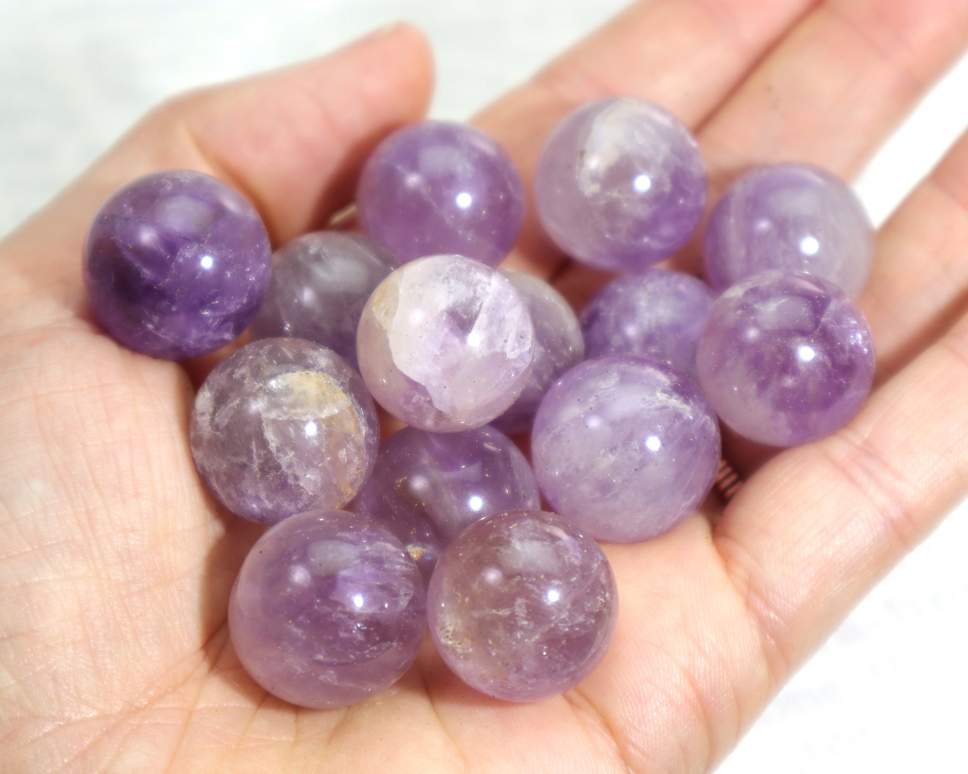 Hand holding a collection of Purple quartz crystal spheres intuitive meditation stones 