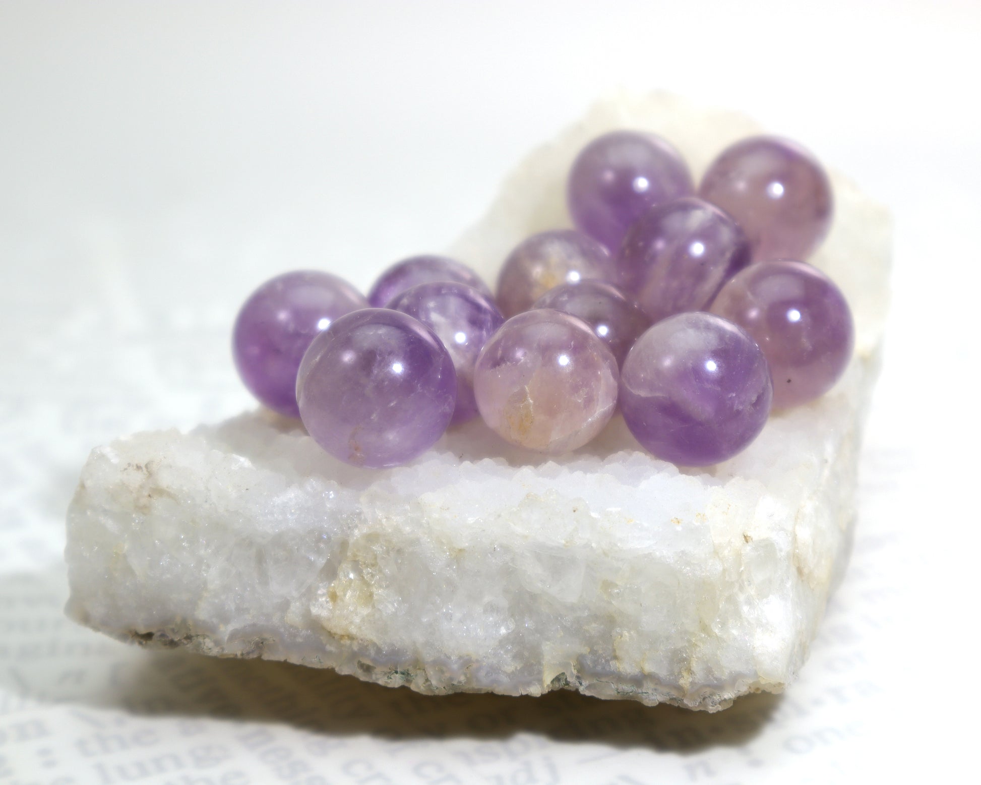 Natural amethyst gemstone spheres on white quartz crystal cluster base
