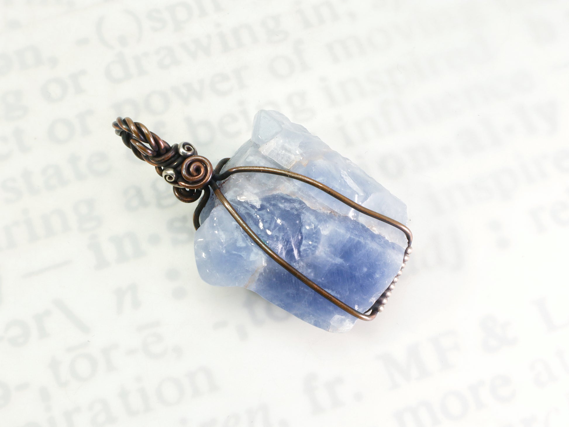 Blue calcite wire wrapped pendant shown on neutral jewelry background