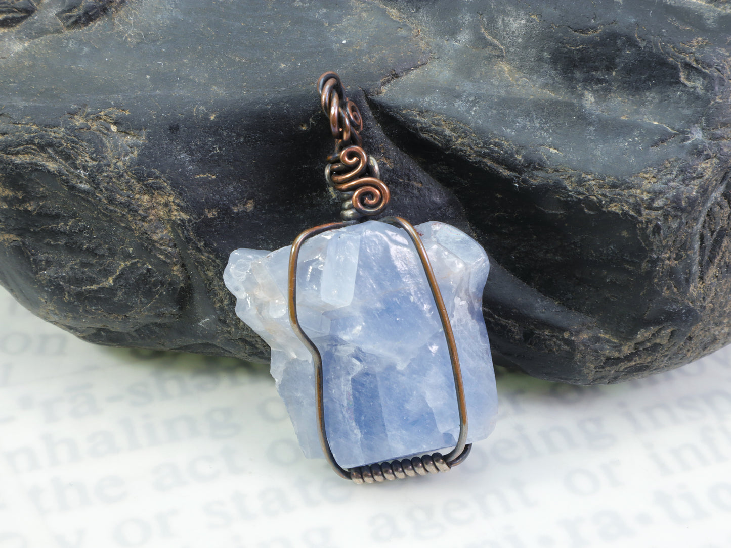 OOAK blue calcite gemstone pendant handmade in oxidized copper and silver in front of a black rock