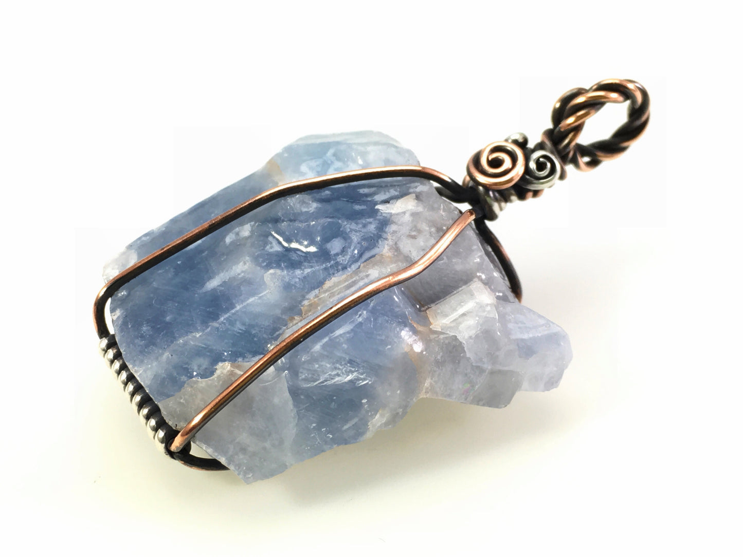 Handmade blue calcite gemstone pendant with antiqued copper and silver wire on a white background