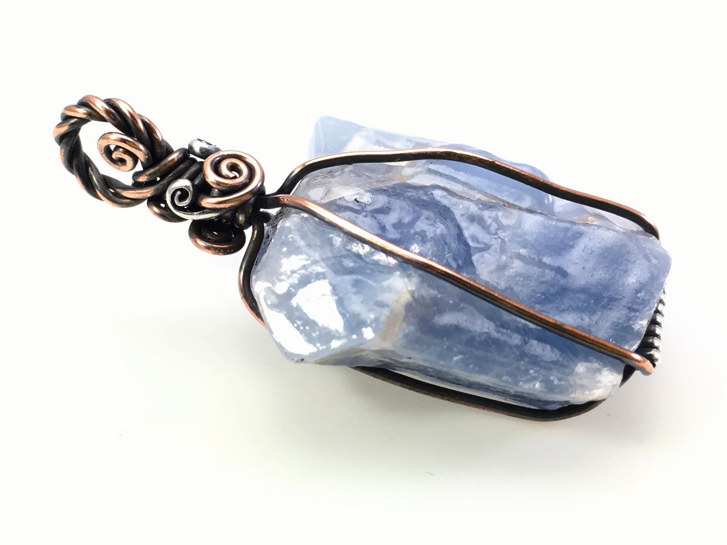 One of a kind blue calcite pendant with copper and sterling silver wire on a white background
