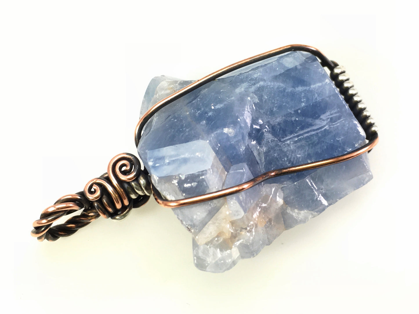Lightly polished blue calcite specimen pendant with rough crystal shape on a white background