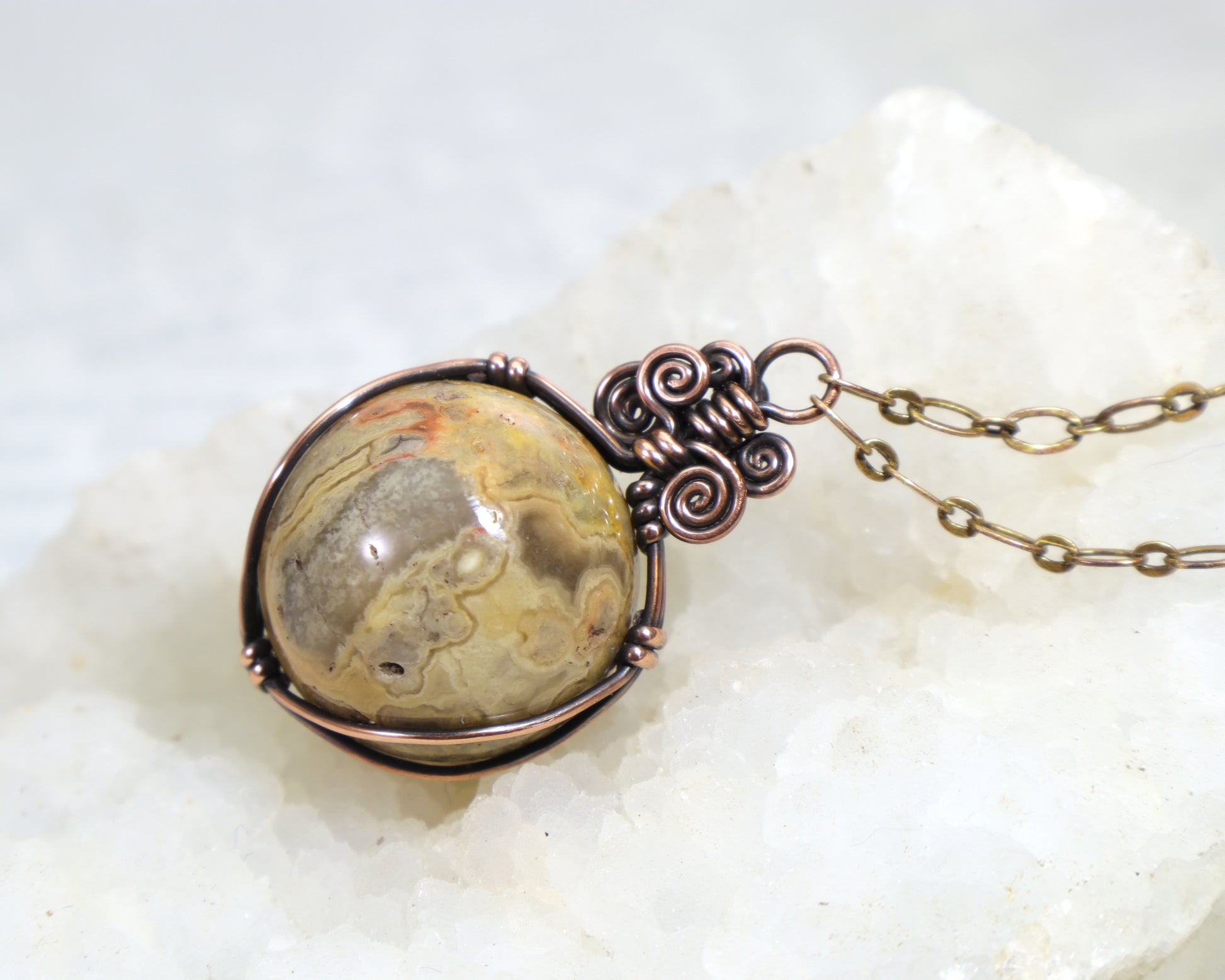 Natural yellow crazy lace agate sphere with intricate banding patterns