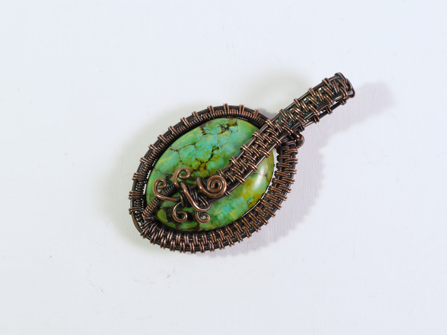 Bright green gemstone pendant with decorative copper wirework