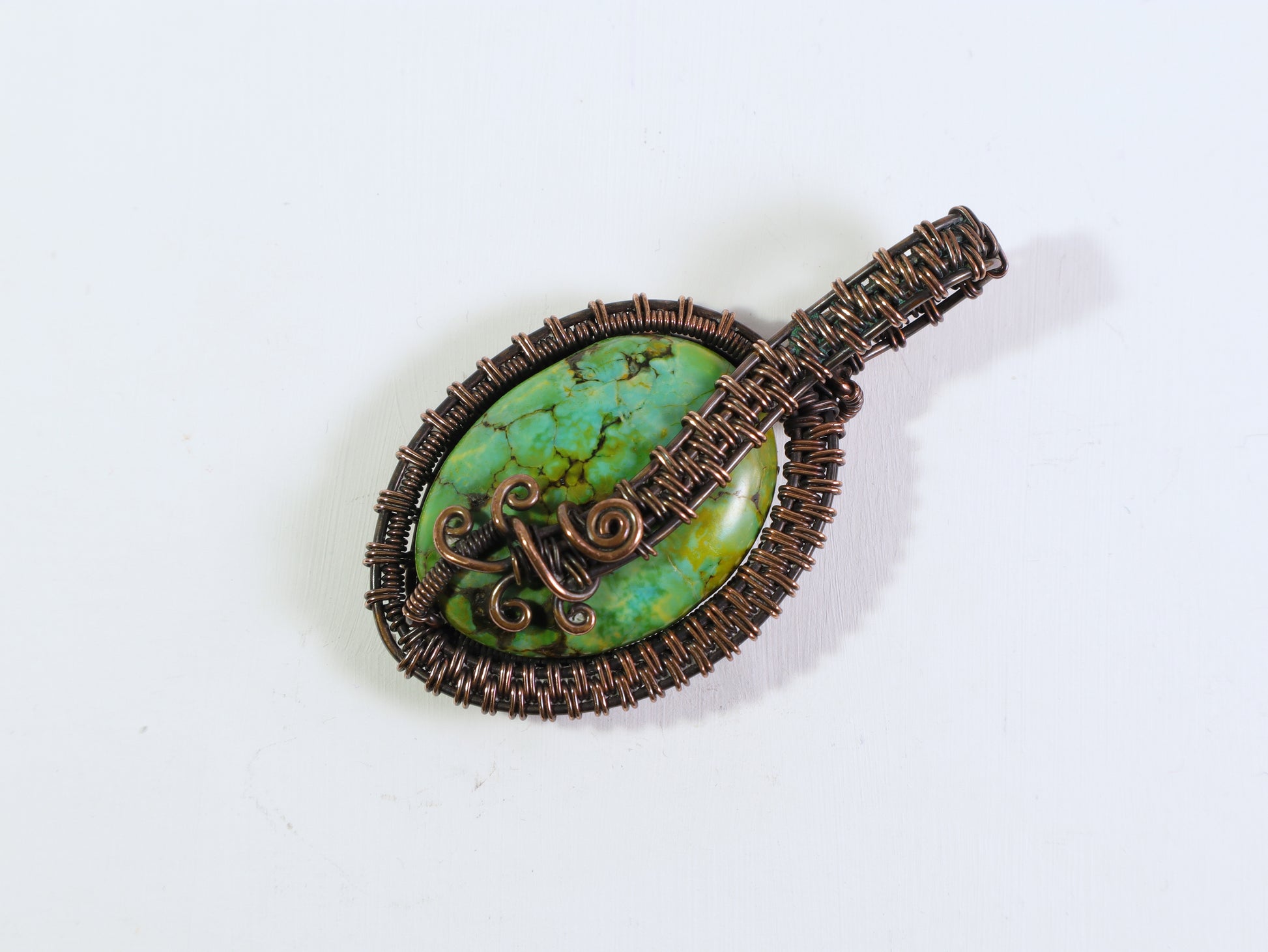 Bright green gemstone pendant with decorative copper wirework