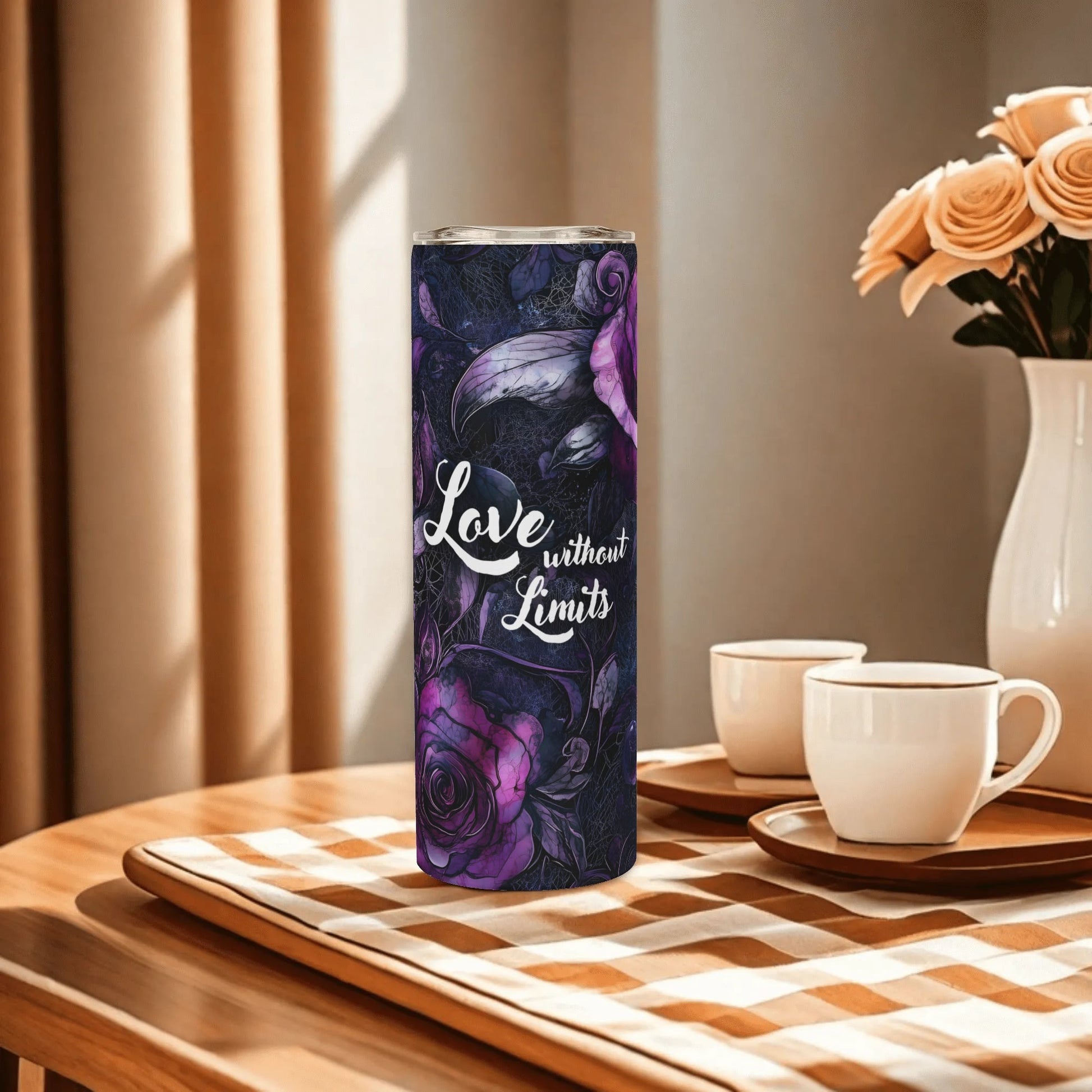 Tumbler with floral design and 'Love without Limits' text on a table with cups and flowers.