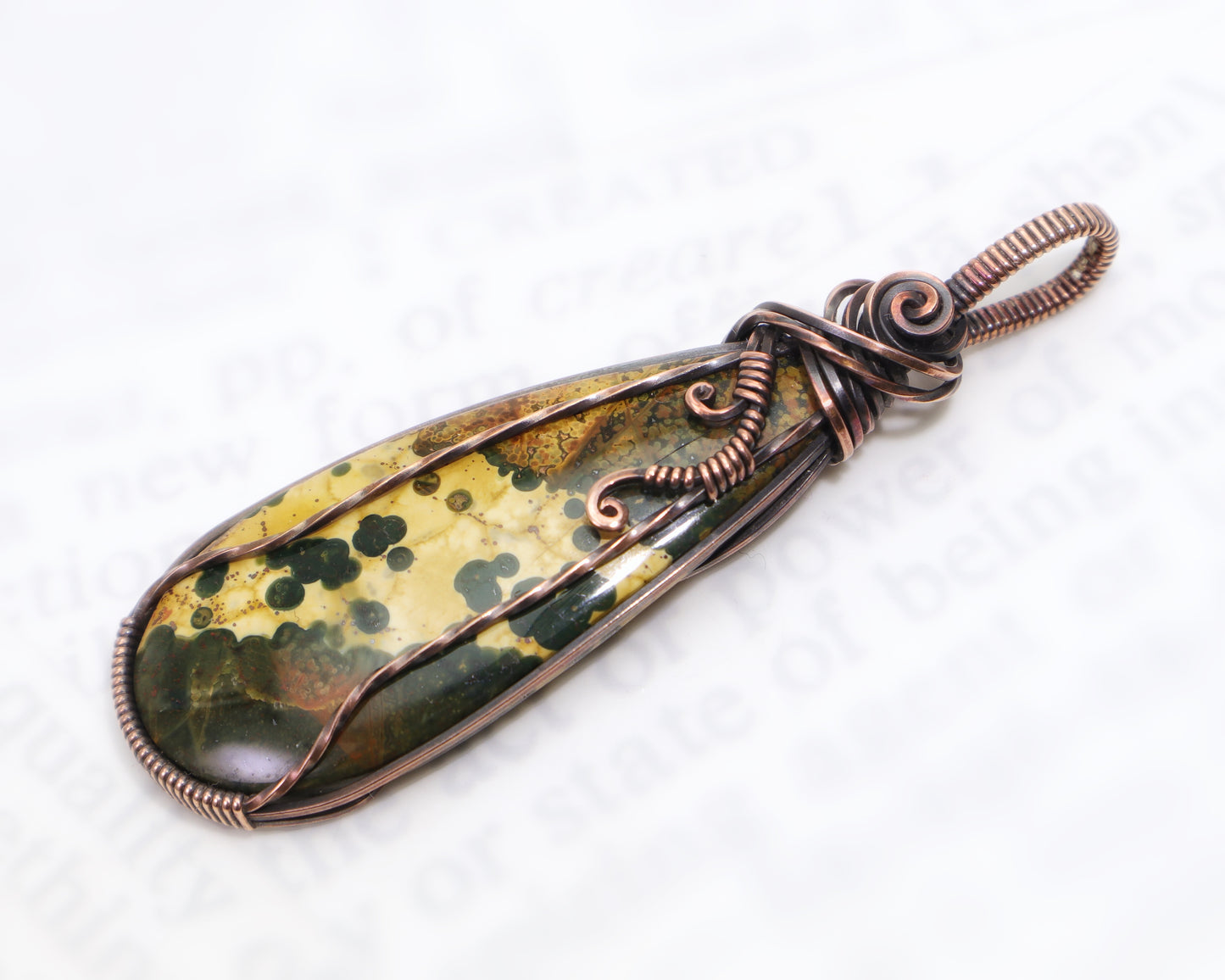 Ocean Jasper crystal pendant photographed outdoors on stone