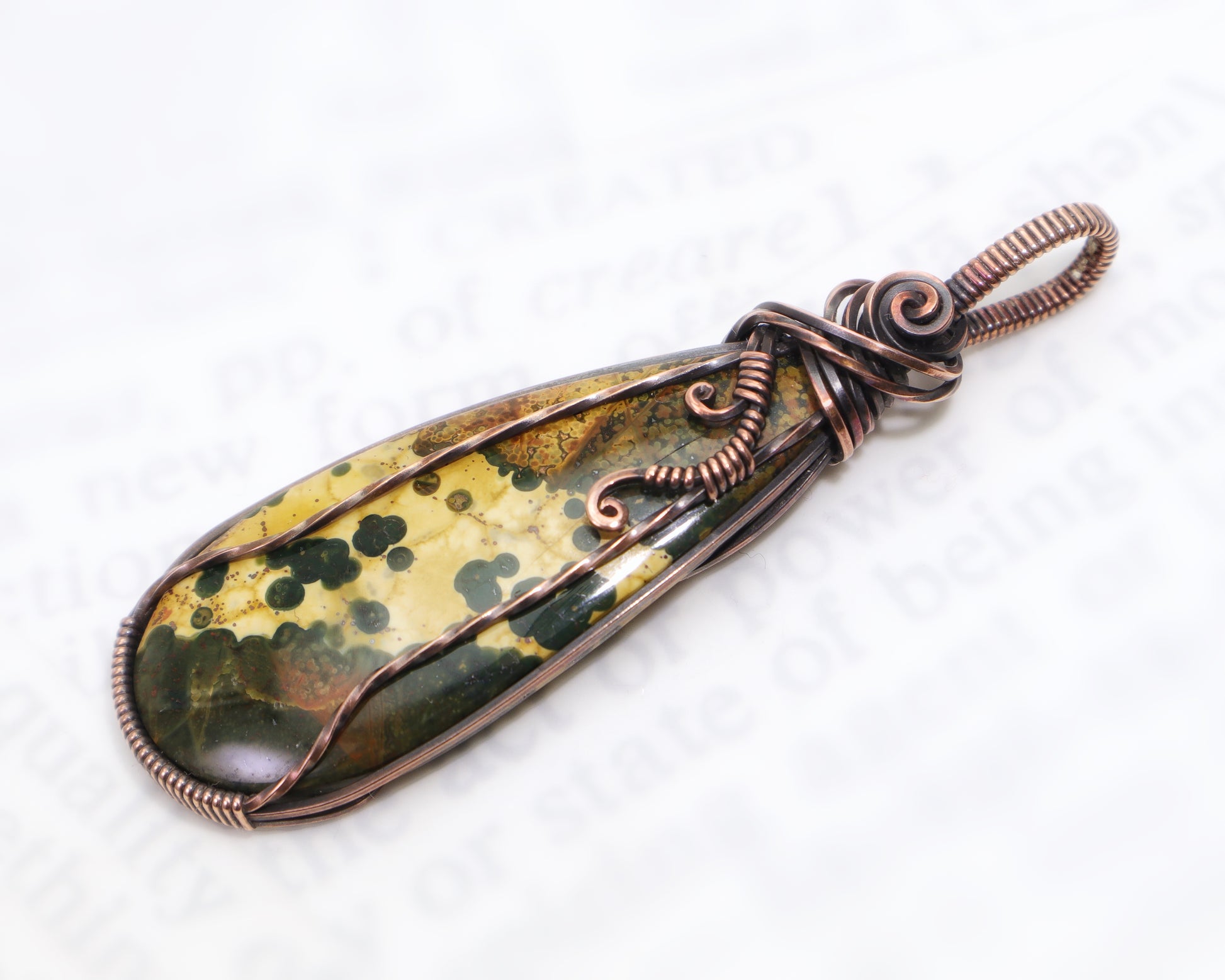 Ocean Jasper crystal pendant photographed outdoors on stone