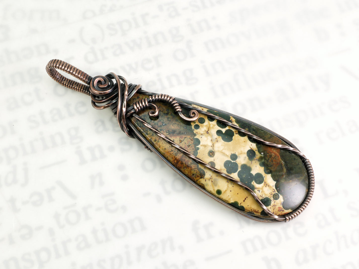 Ocean Jasper pendant wire wrapped in oxidized copper on a white background