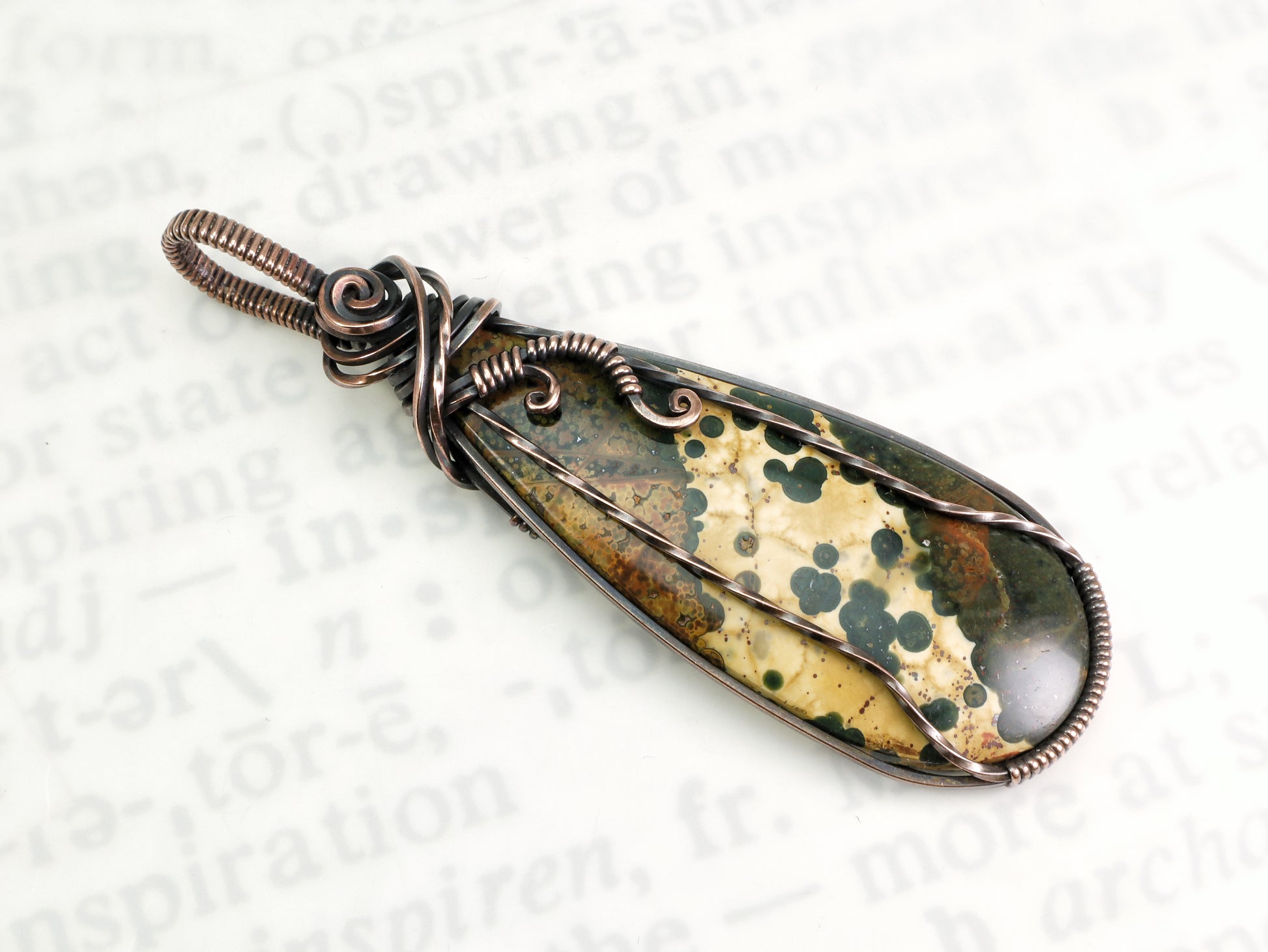 Ocean Jasper pendant wire wrapped in oxidized copper on a white background