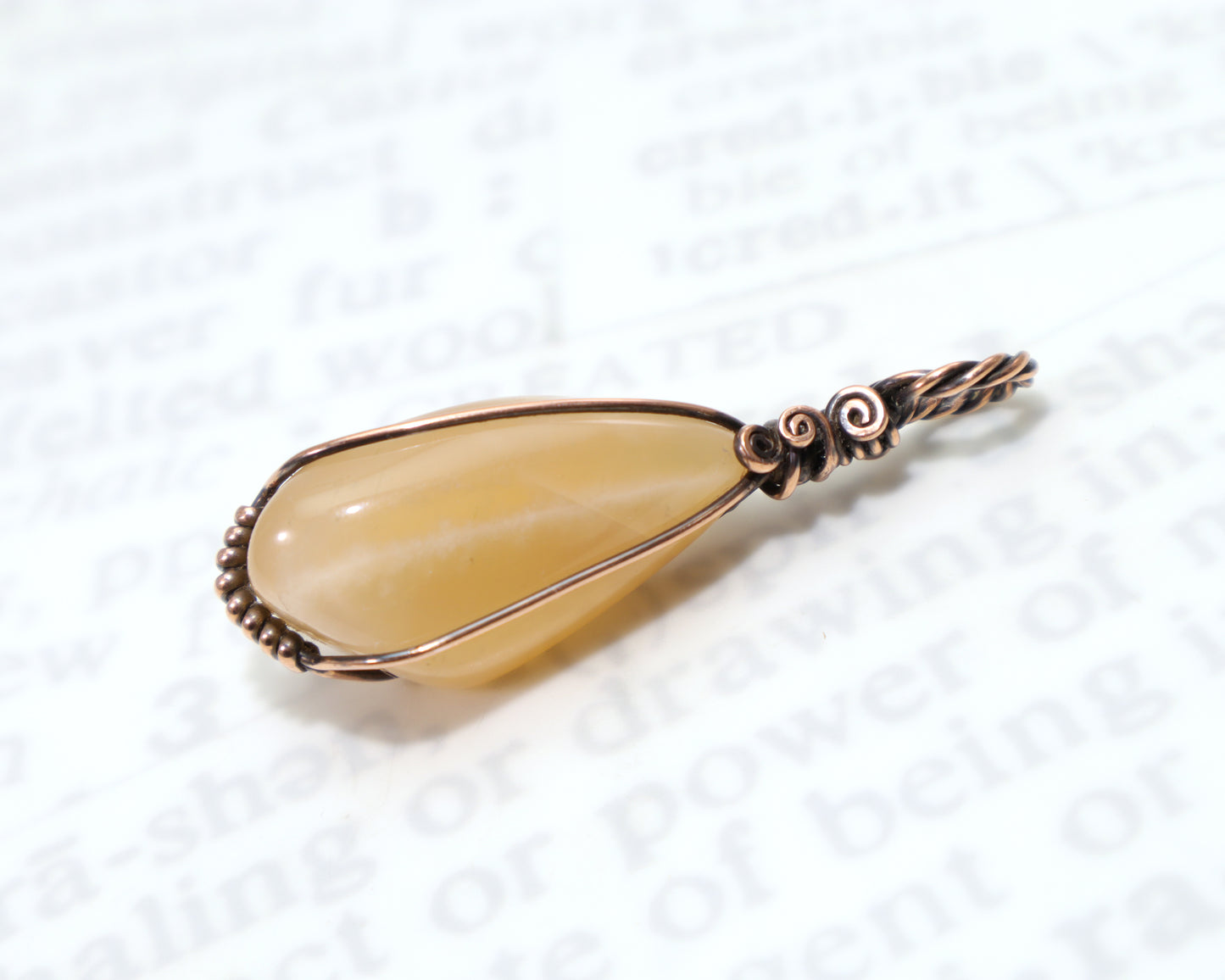 Peach moonstone healing crystal pendant with decorative copper spirals