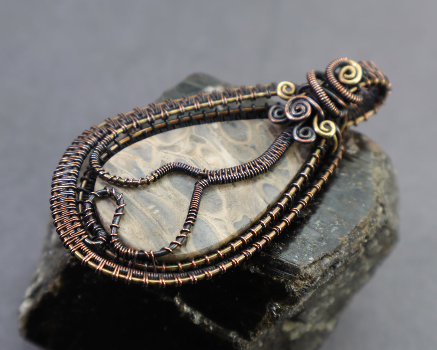 Backside of wire woven fossil pendant featuring natural orb palmwood patterns