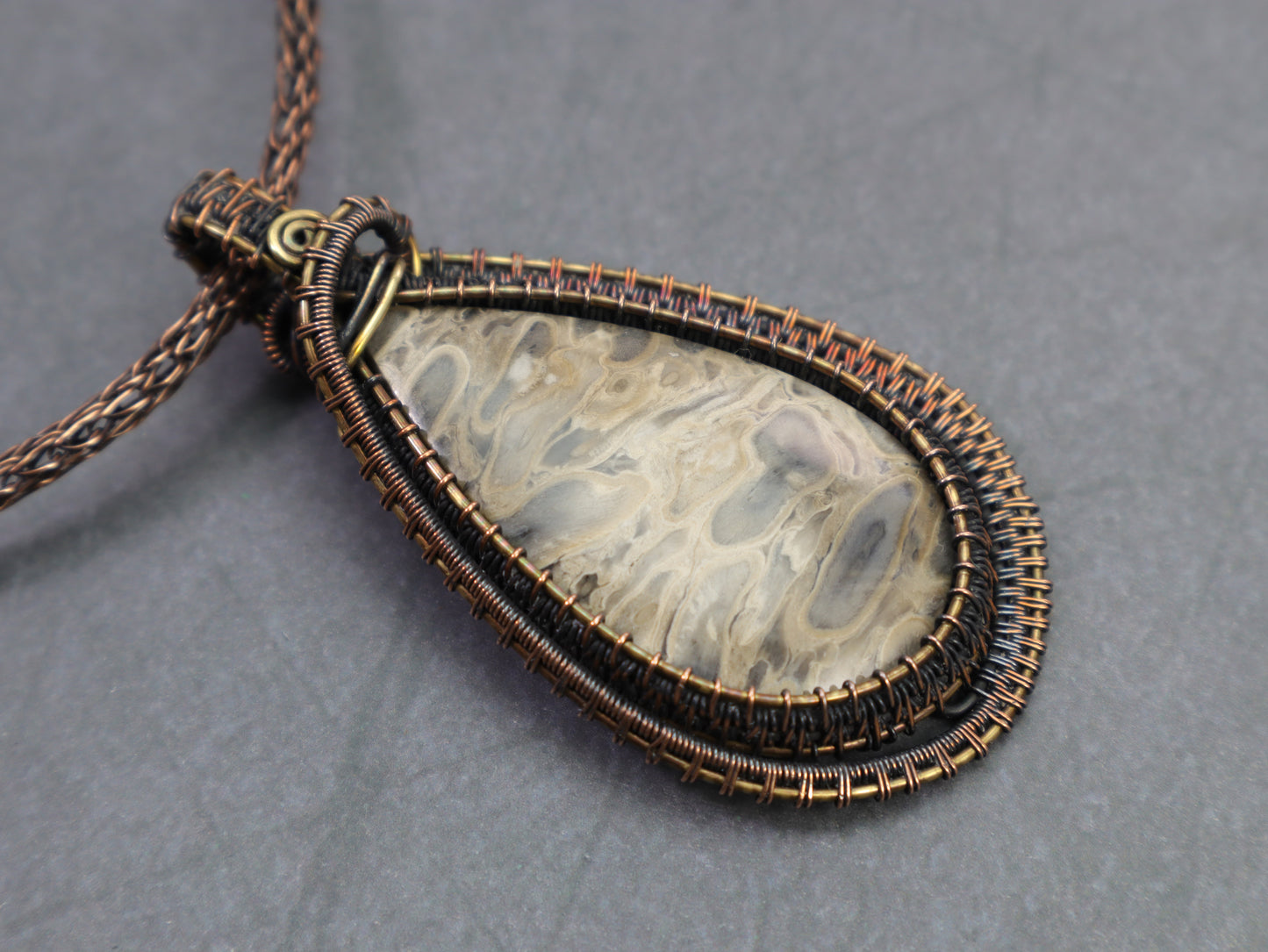 Handmade copper and brass petrified wood pendant with detailed weaving