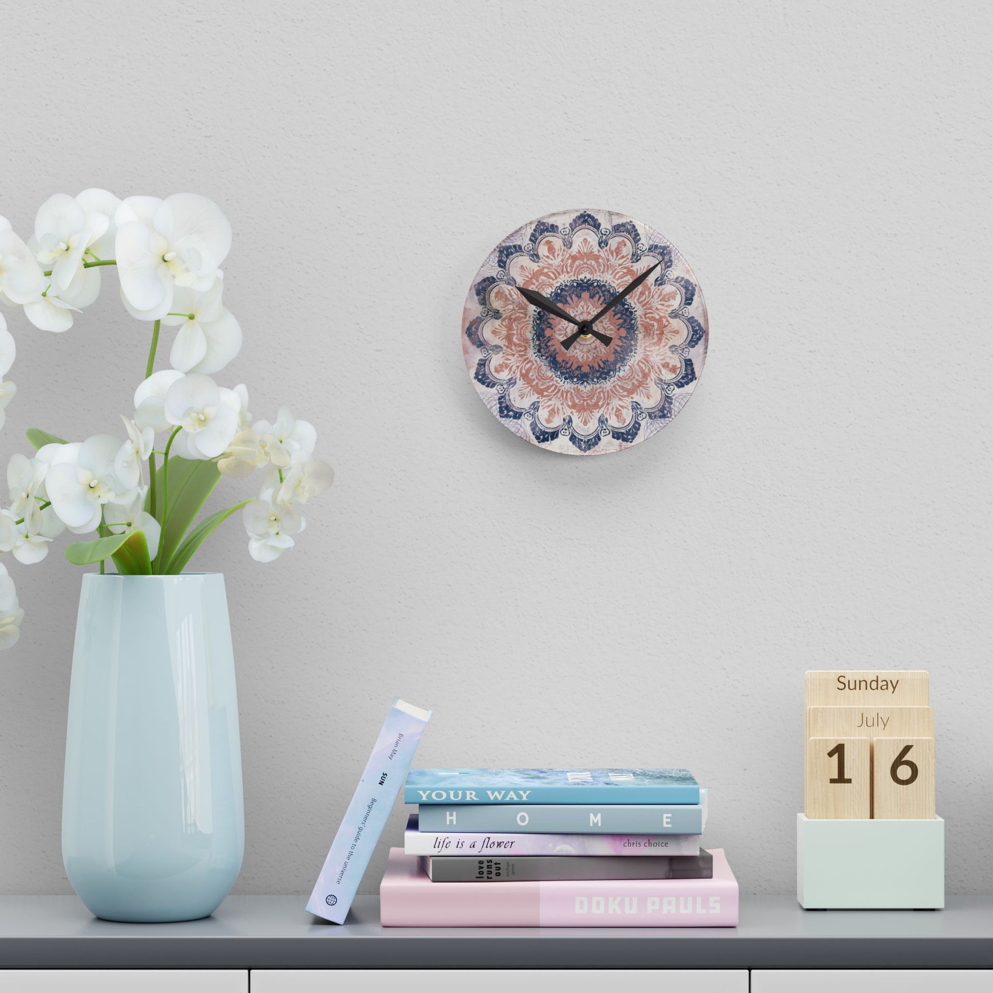 Small rose pink and navy blue mandala wall clock displayed above books and floral decor
