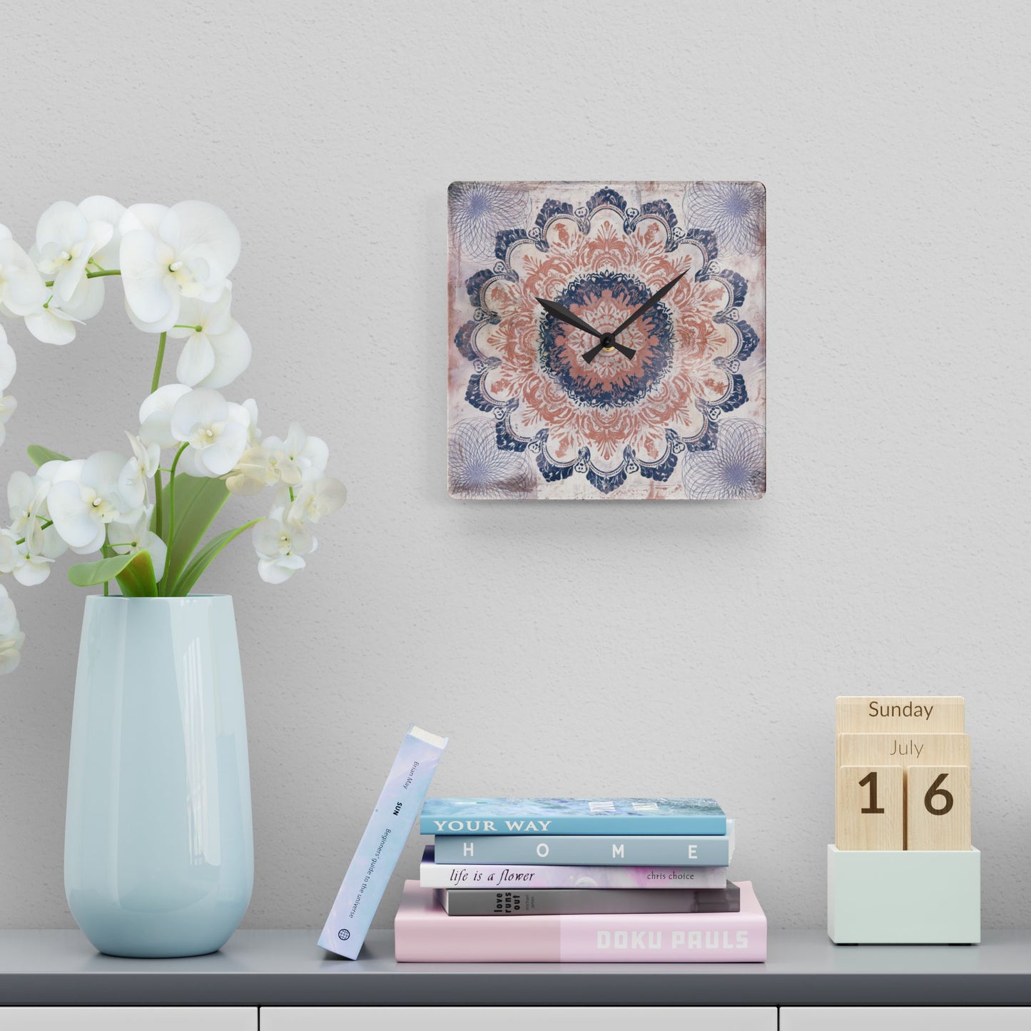 Decorative boho mandala wall clock displayed above books and white orchid arrangement