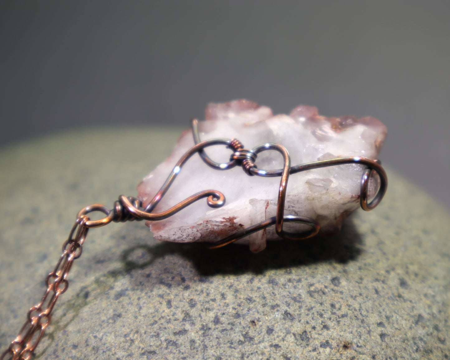 Back side of natural ferruginous quartz cluster pendant wrapped in oxidized copper