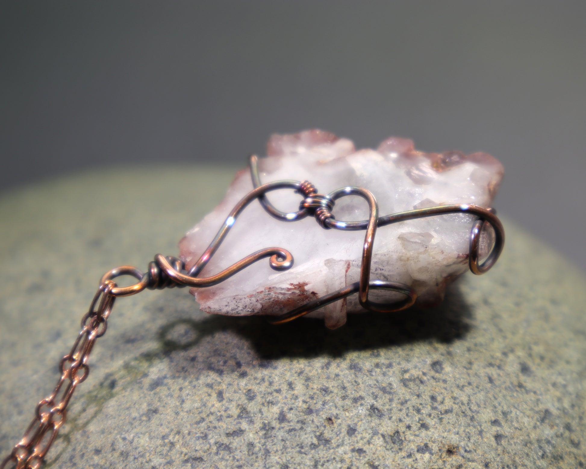 Back side of natural ferruginous quartz cluster pendant wrapped in oxidized copper