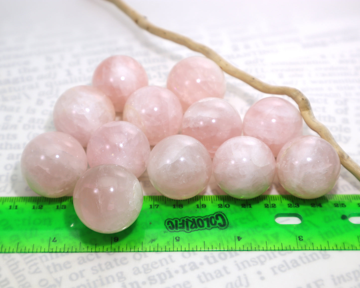 Natural rose quartz spheres 27–29mm polished pink crystal balls sitting on a white background with a green ruler and a small piece of driftwood.