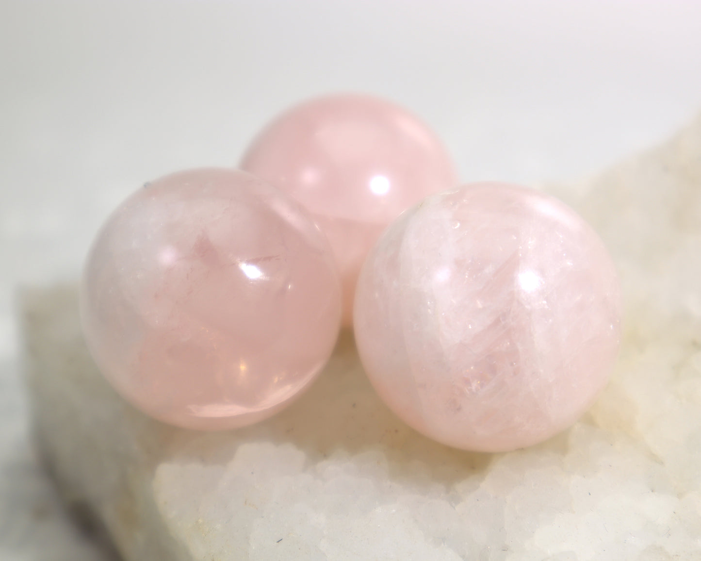 Three rose quartz crystal balls showing natural clouding and flecks