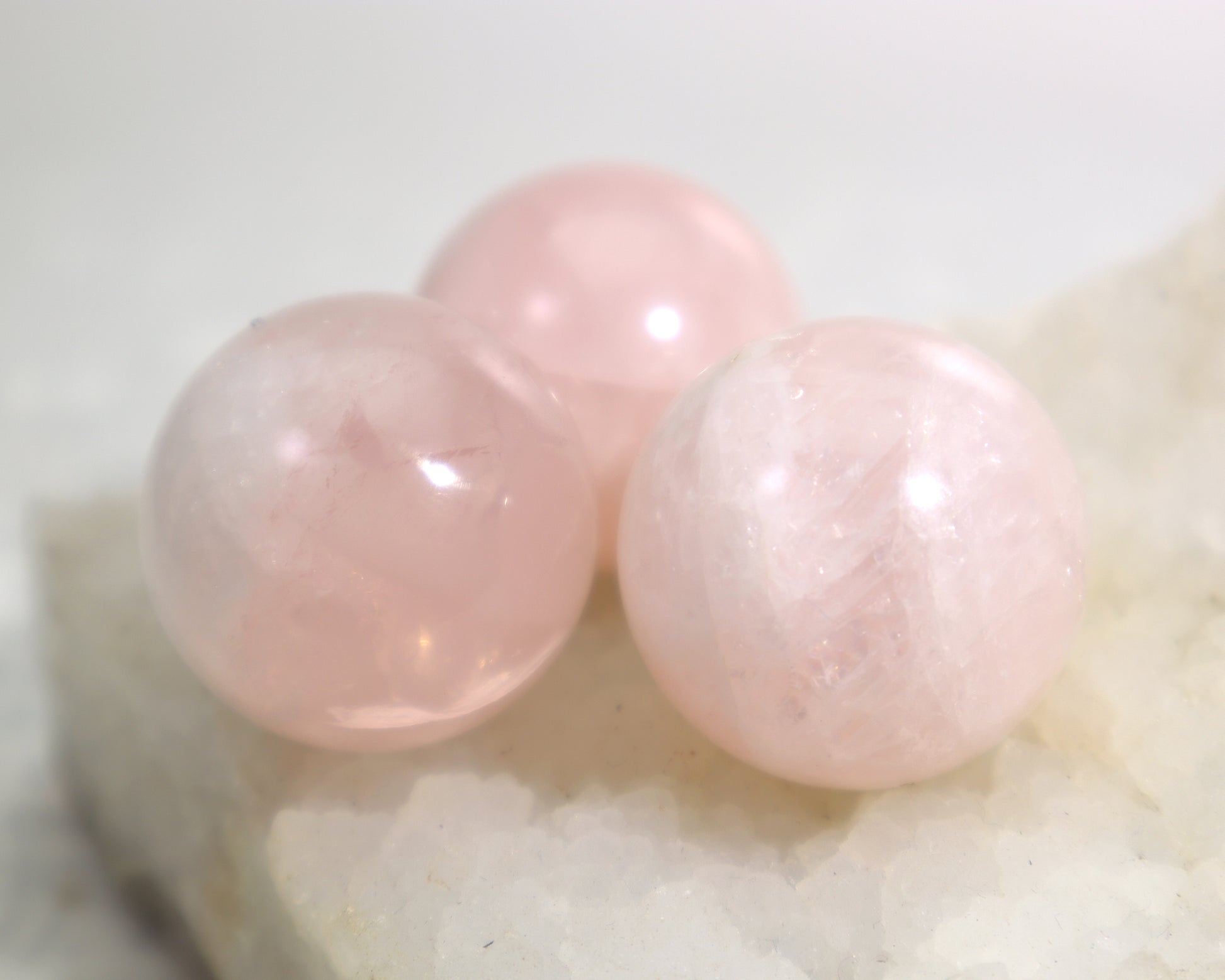 Three rose quartz crystal balls showing natural clouding and flecks