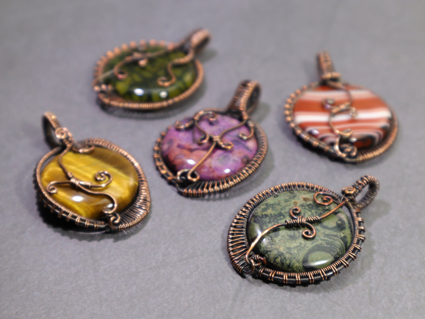 Artisan wire woven gemstone pendants with flowing copper wirework. The stones shown are dragon vein agate, sardonyx, crazy lace agate, tiger eye and kambaba jasper.