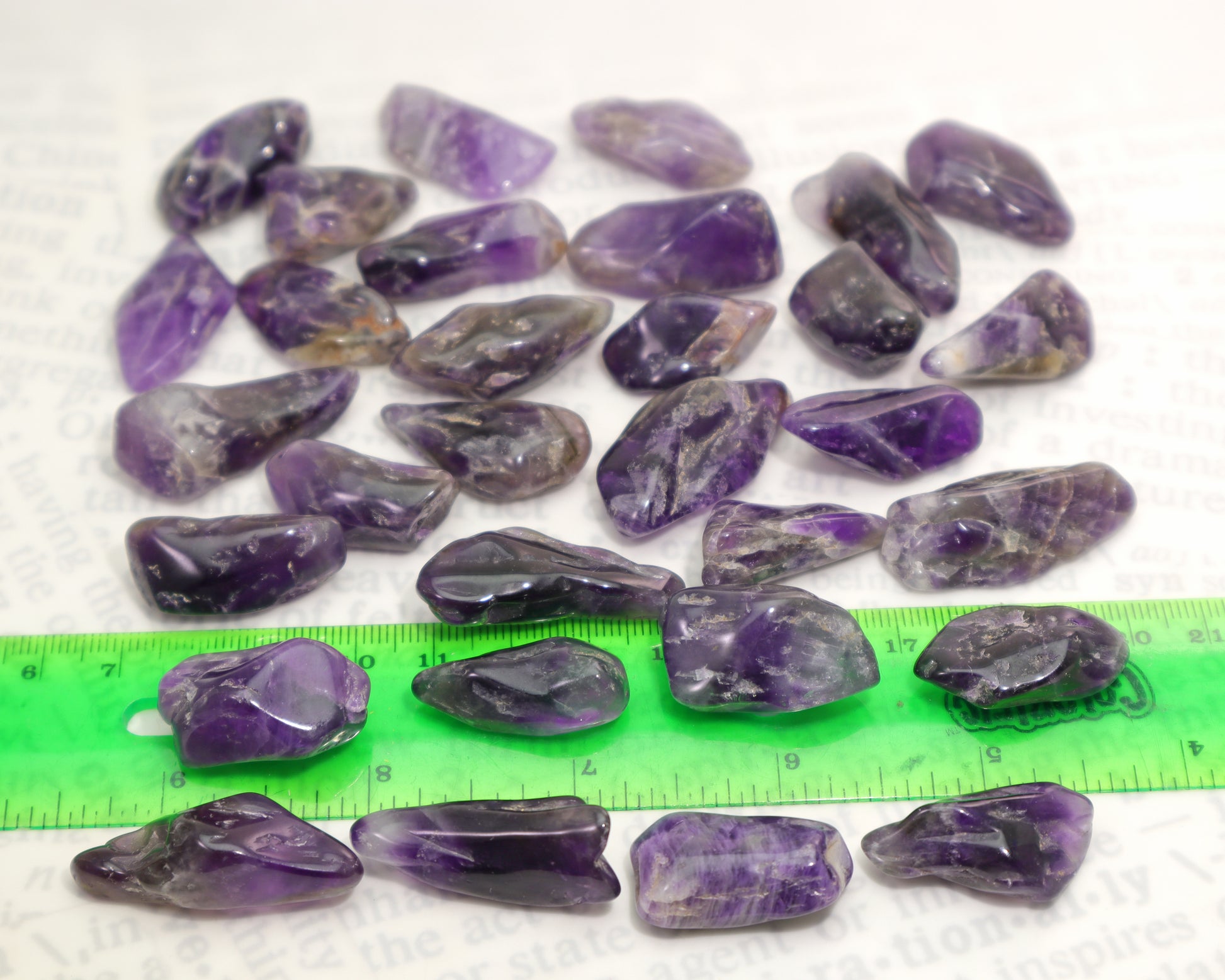 Tumbled amethyst stones with ruler for size reference